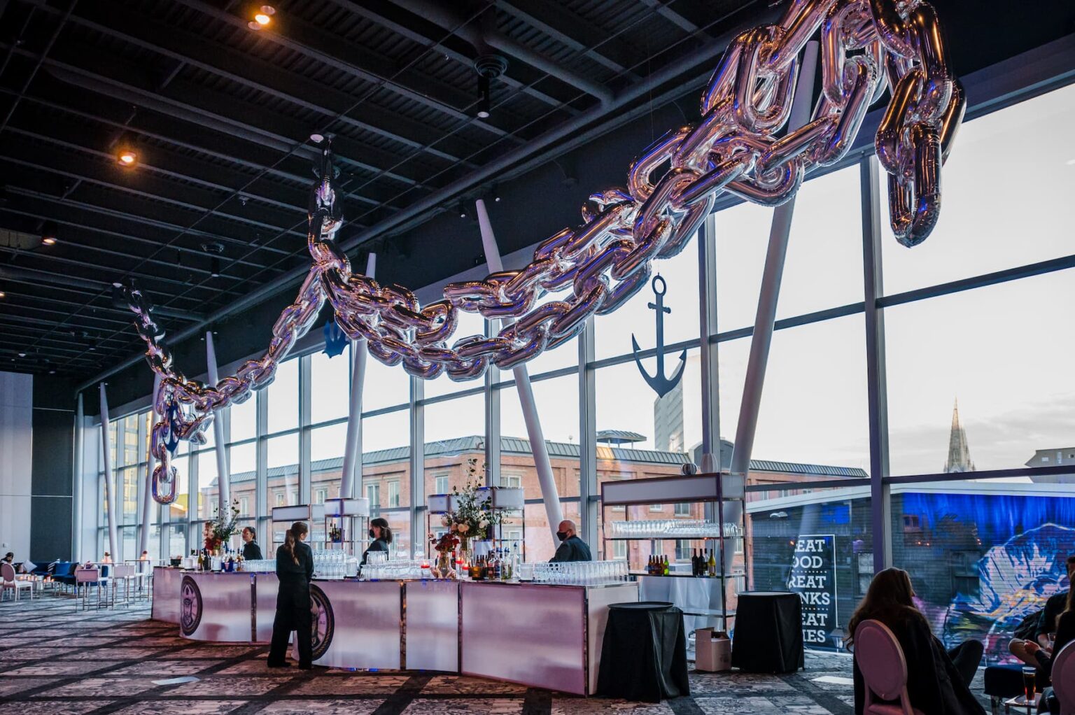 Modern event venue with a stylish bar setup and a unique decorative chain installation, creating a sophisticated ambiance for guests.